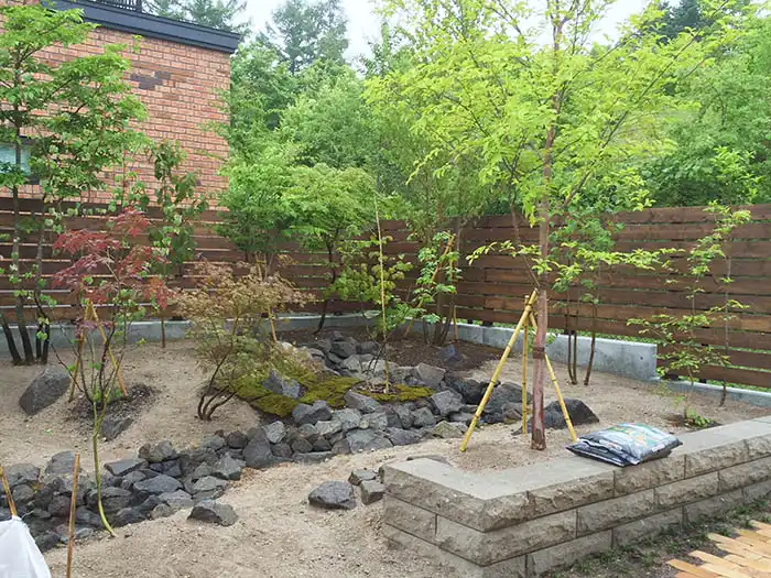 板塀で囲まれた雑木と流れのある庭